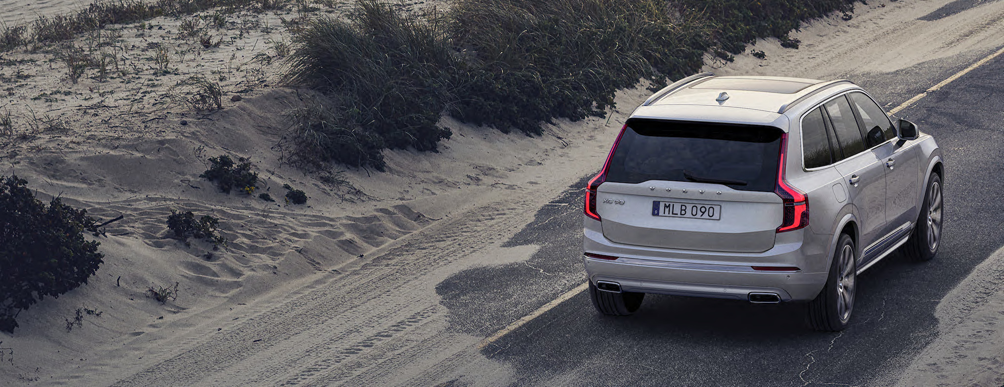 Volvo XC90 steht auf einer Straße vor Dünen – Rückansicht