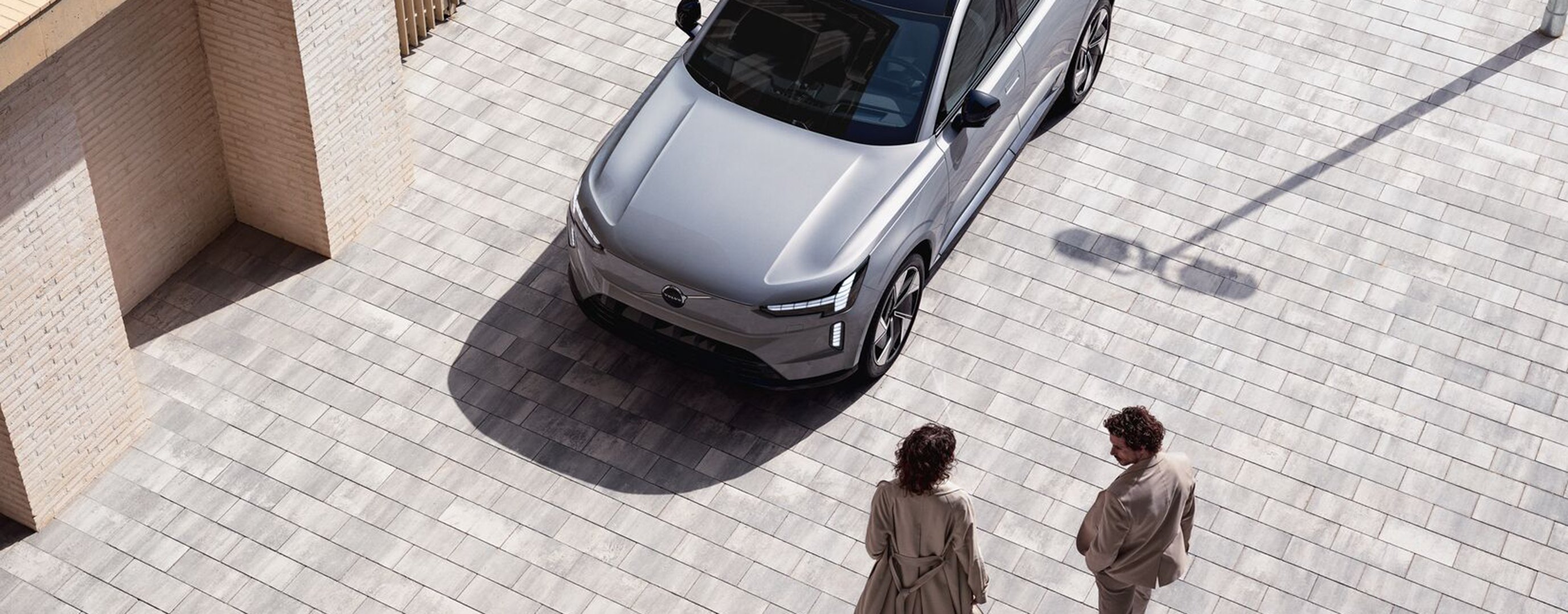 Drei Menschen stehen an Autohaus um den Volvo XC40 Pure Electric