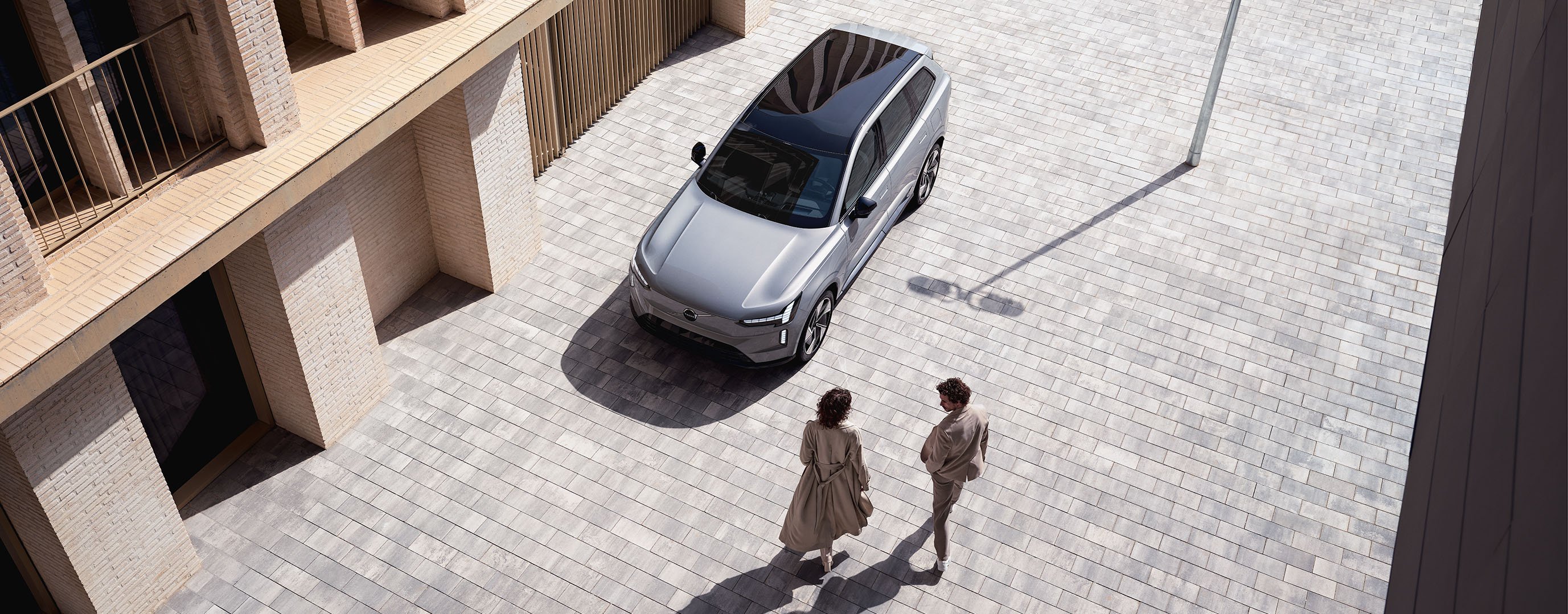 Drei Menschen stehen an Autohaus um den Volvo XC40 Pure Electric