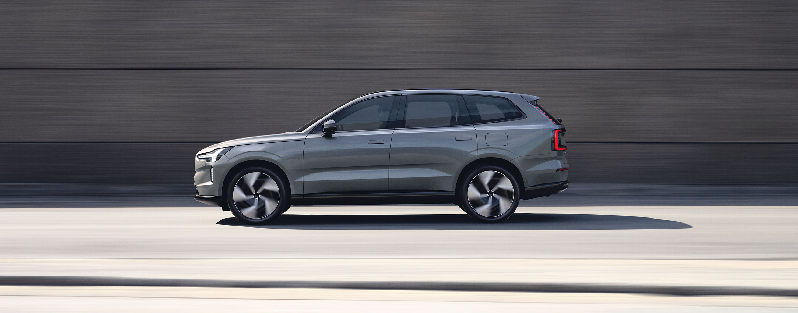 Frau läuft weg von einem grauen Volvo.