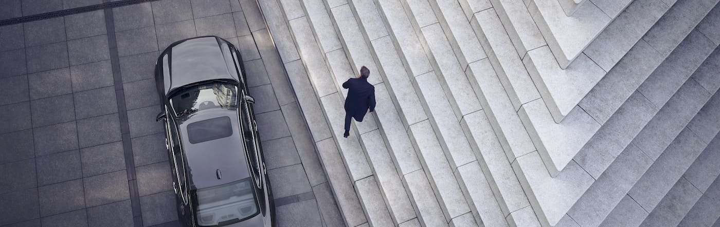 Mann geht auf Treppe von einem Volvo S90 weg