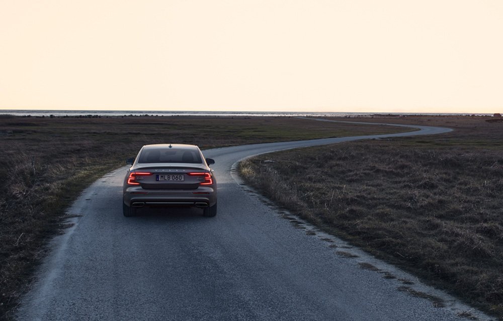 Grauer Volvo vor einer Meer Kulisse. Mann steht neben Volvo.