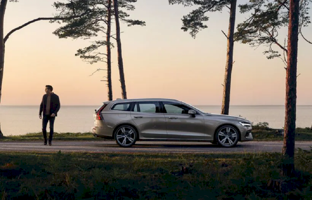 Grauer Volvo vor einer Meer Kulisse. Mann steht neben Volvo.